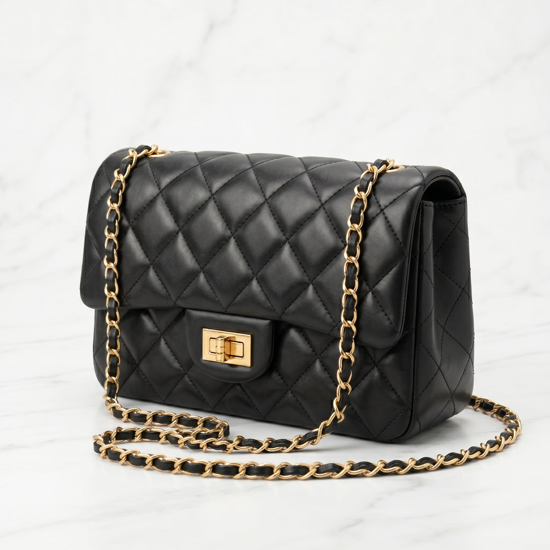 Black quilted handbag with gold chain strap on a white background