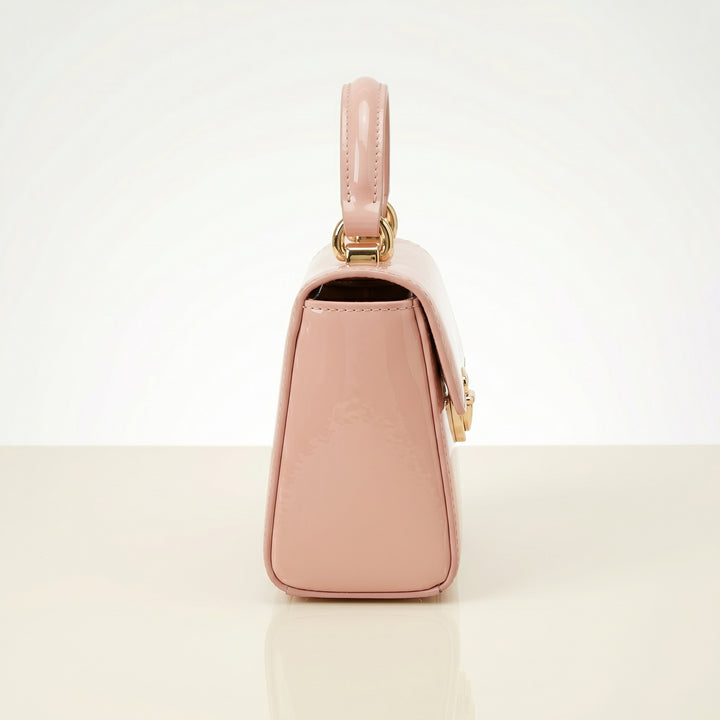 Pink handbag with gold accents on a light beige background
