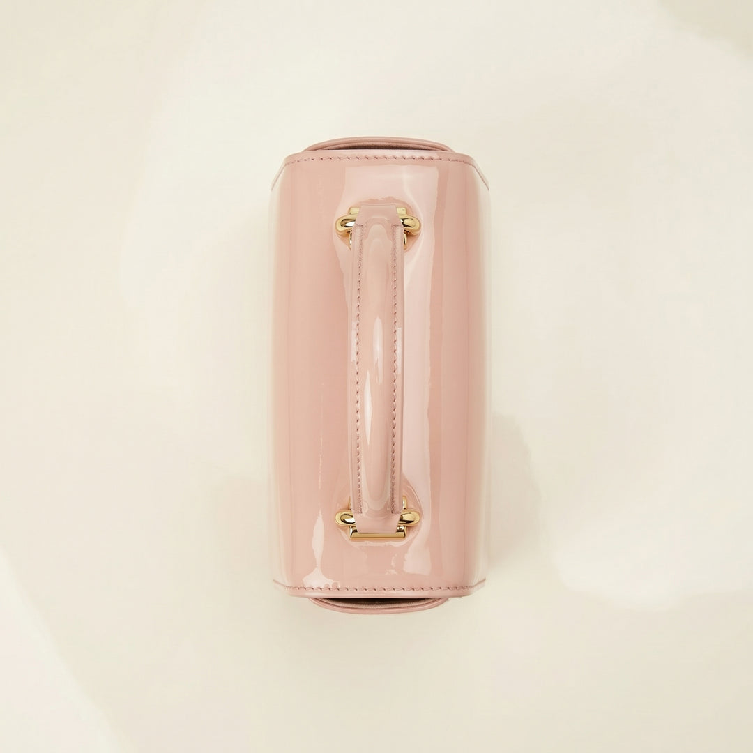 Pink handbag with gold handle on a beige top