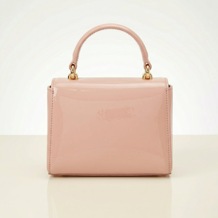 Pink handbag with gold handle on a light beige background