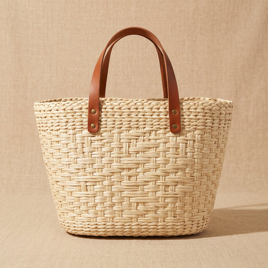 Woven basket with leather handles on a beige background
